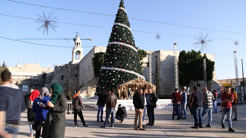 Church of Nativity in the middle of the square with people milling around.