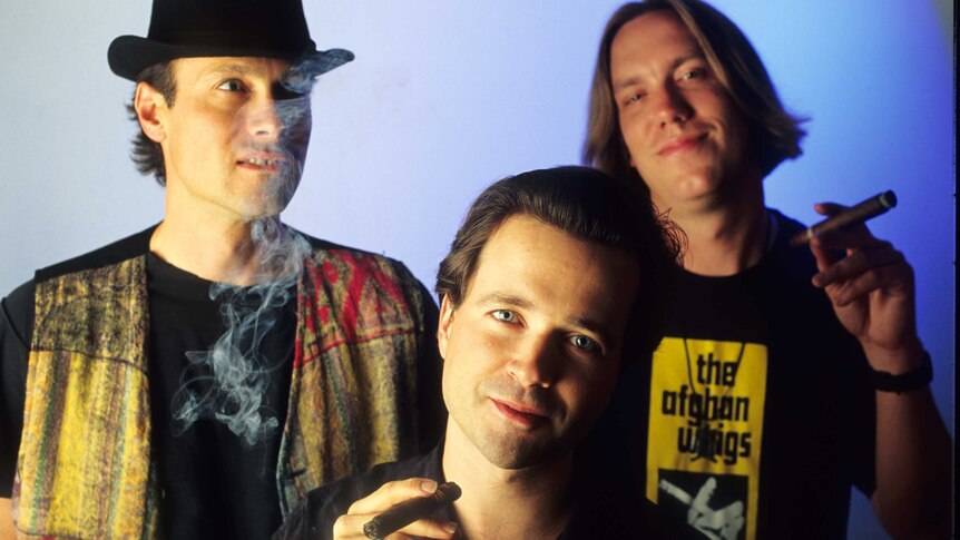 The Violent Femmes, Gordon Gano, Brian Ritchie and Guy Hoffman, smoking a cigar during a group portrait.