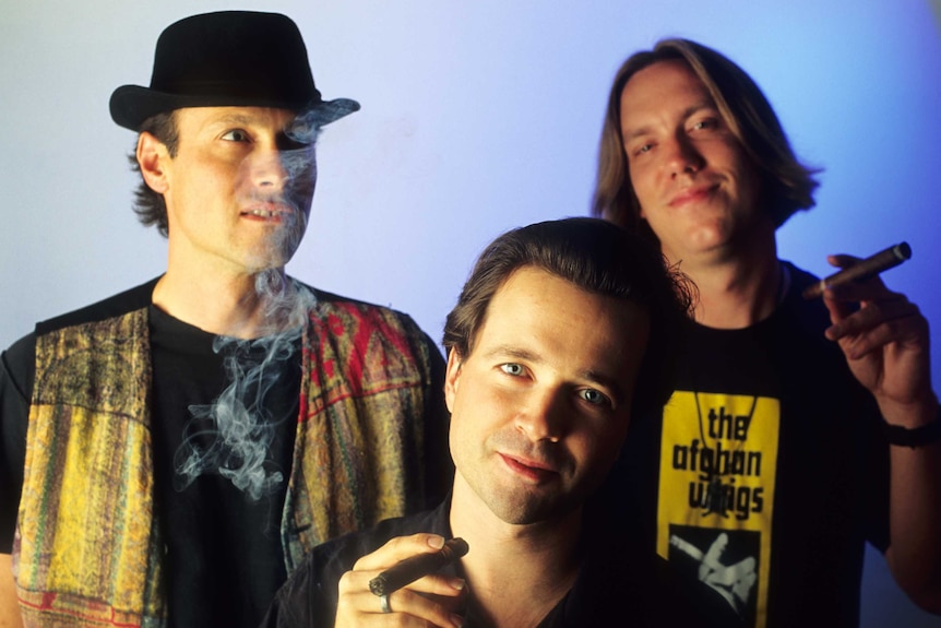 The Violent Femmes, Gordon Gano, Brian Ritchie and Guy Hoffman, smoking a cigar during a group portrait.