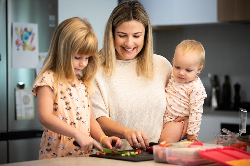 Kyla Smith with her daughter Elsie, 4 and her baby as they prepare food on the kitchen counter