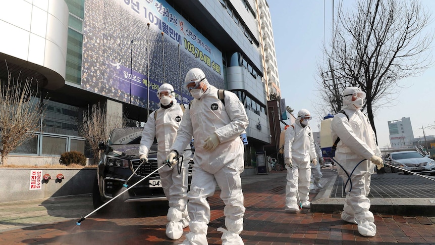 Workers wearing protective gears spray disinfectant against the new coronavirus in South Korea.