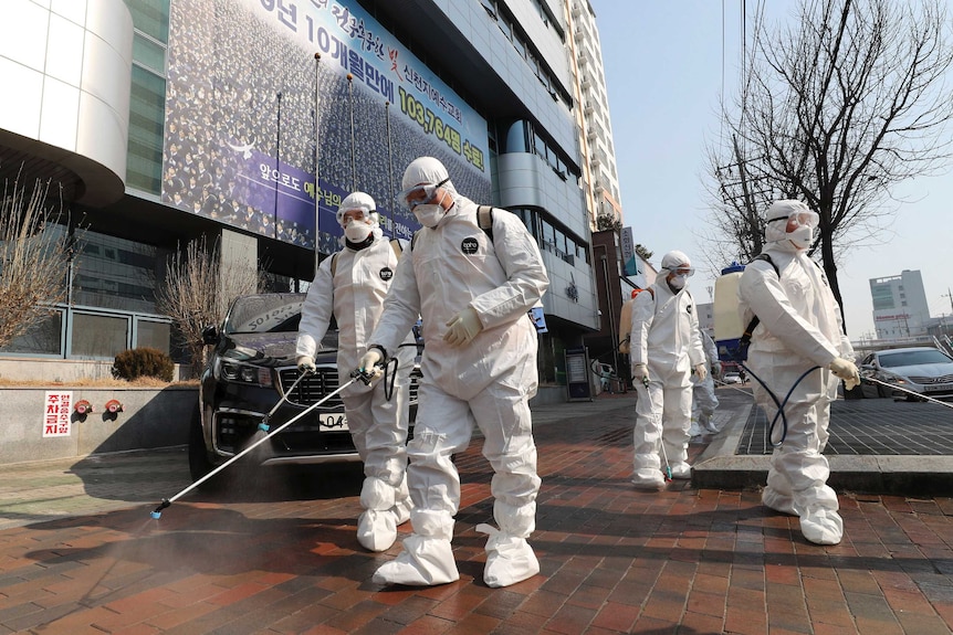 Workers wearing protective gears spray disinfectant against the new coronavirus in South Korea.