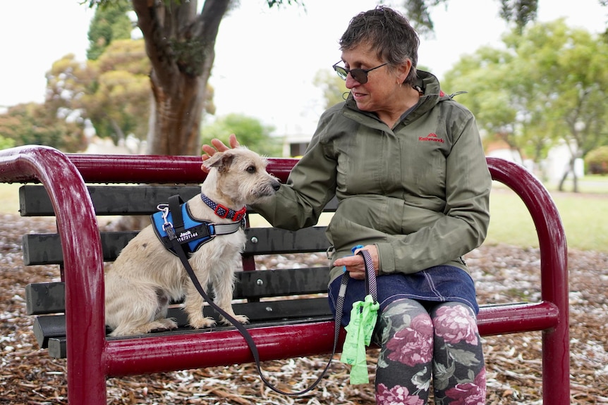 Adelaide woman Nicola Parin with her dog on a suburban park bench.