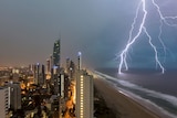 Lightning cracks over city with dark, purple skies above the city at night