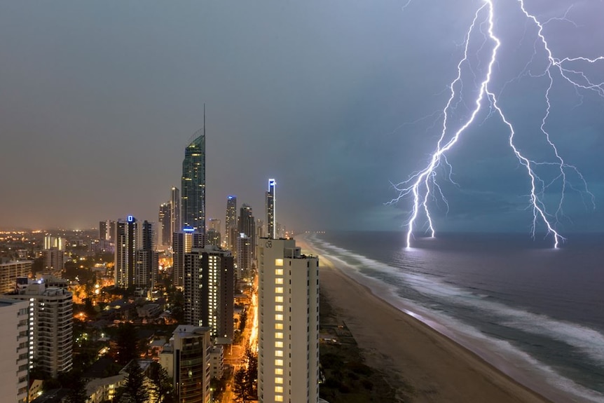 Lightning cracks over city with dark, purple skies above the city at night