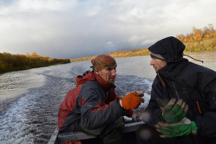Two Gulag expedition members on a small powered boat traversing the Russian Taiga in Autumn.
