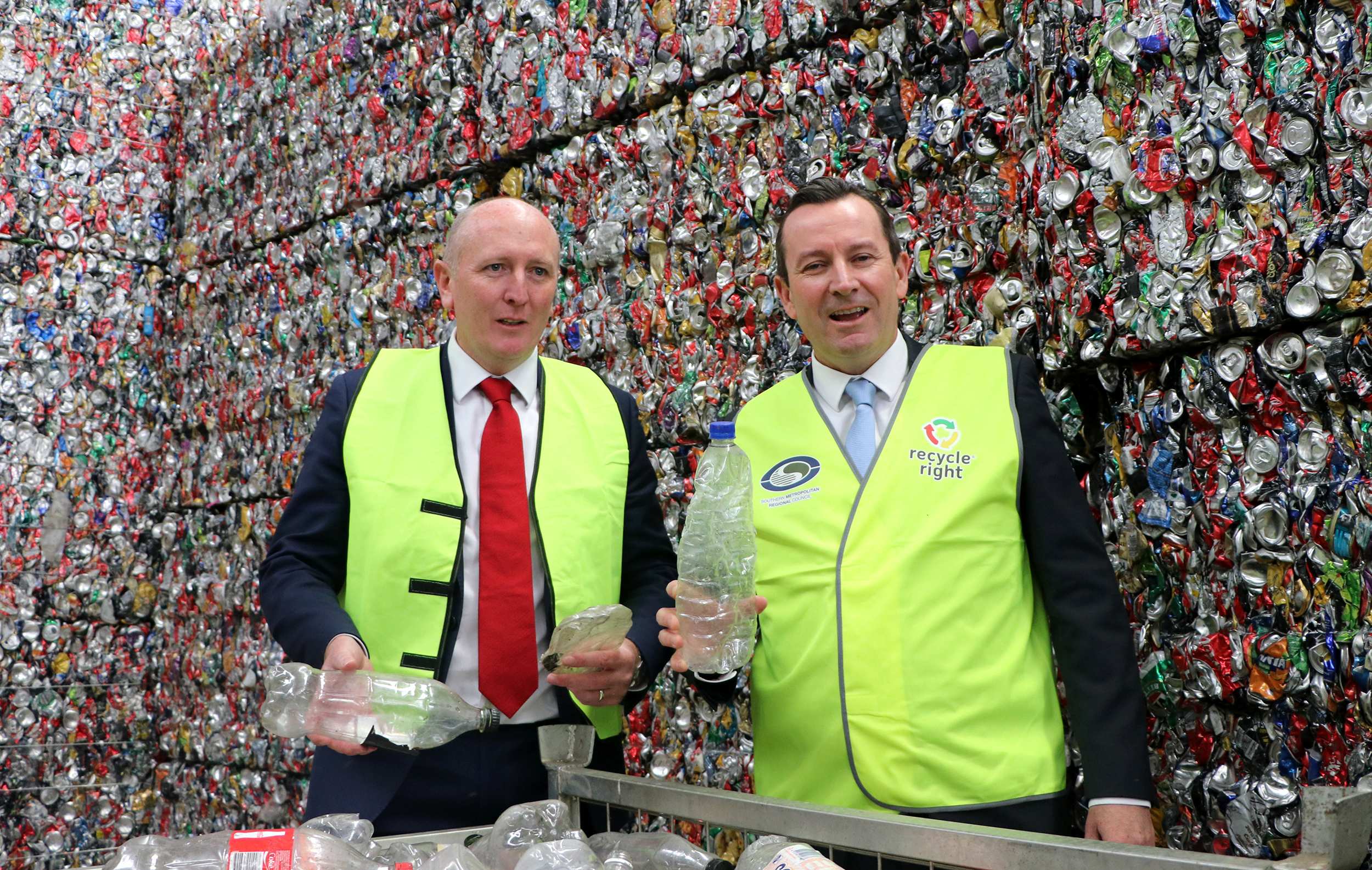 A mid shot of WA Environment Minister Stephen Dawson in front of a giant pile of recycling wearing a hi-vis vest.