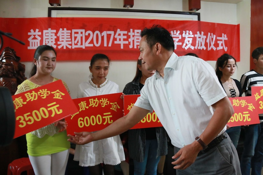 A Xinjiang Yikang representative hands out donations to Uyghur villagers.