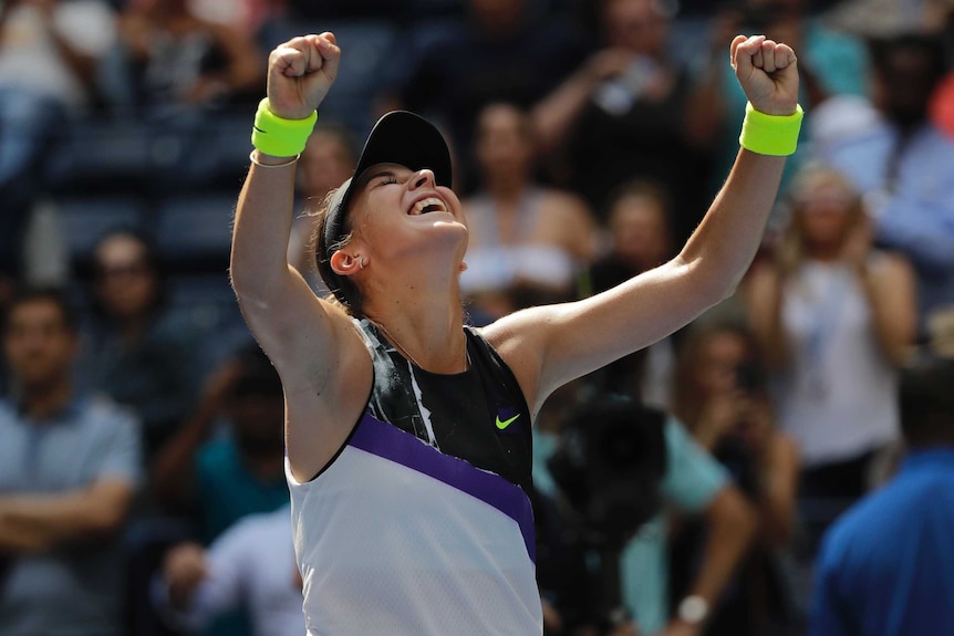 Belinda Bencic tilts her head up to the sky with her eyes closed and mouth open and both arms up with fists clenched