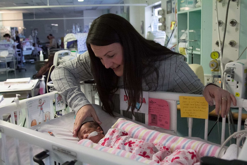 Voula Pappas with her daughter Dimitri at her crib in the Newborn Intensive Care Unit