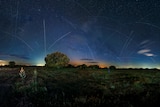 Night in a country area. Satellite trails a visible throughout the sky.