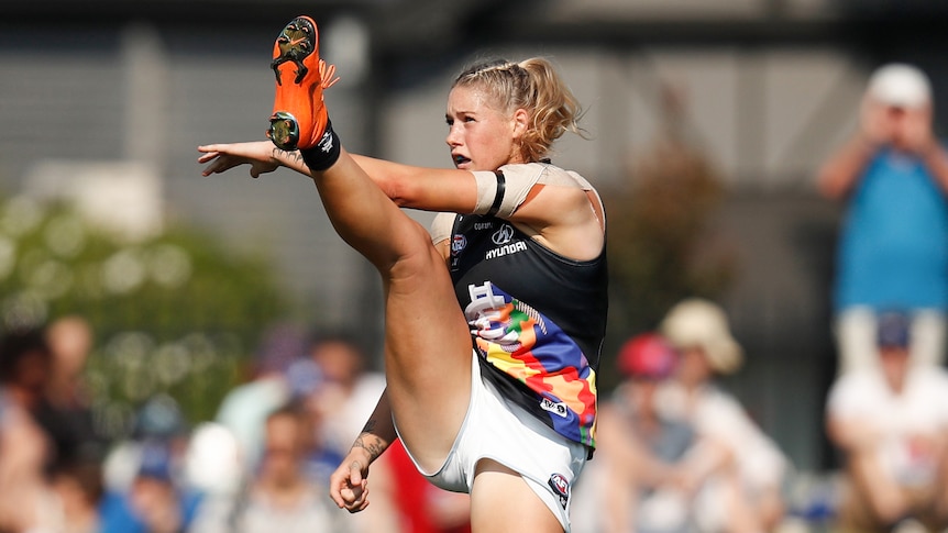 AFLW player in the action of kicking the ball during a match