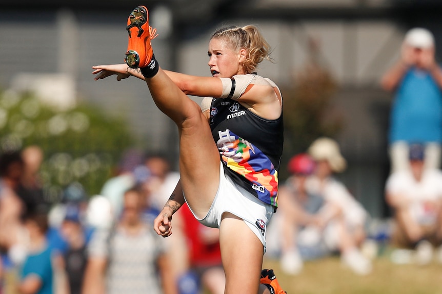 AFLW player in the action of kicking the ball during a match
