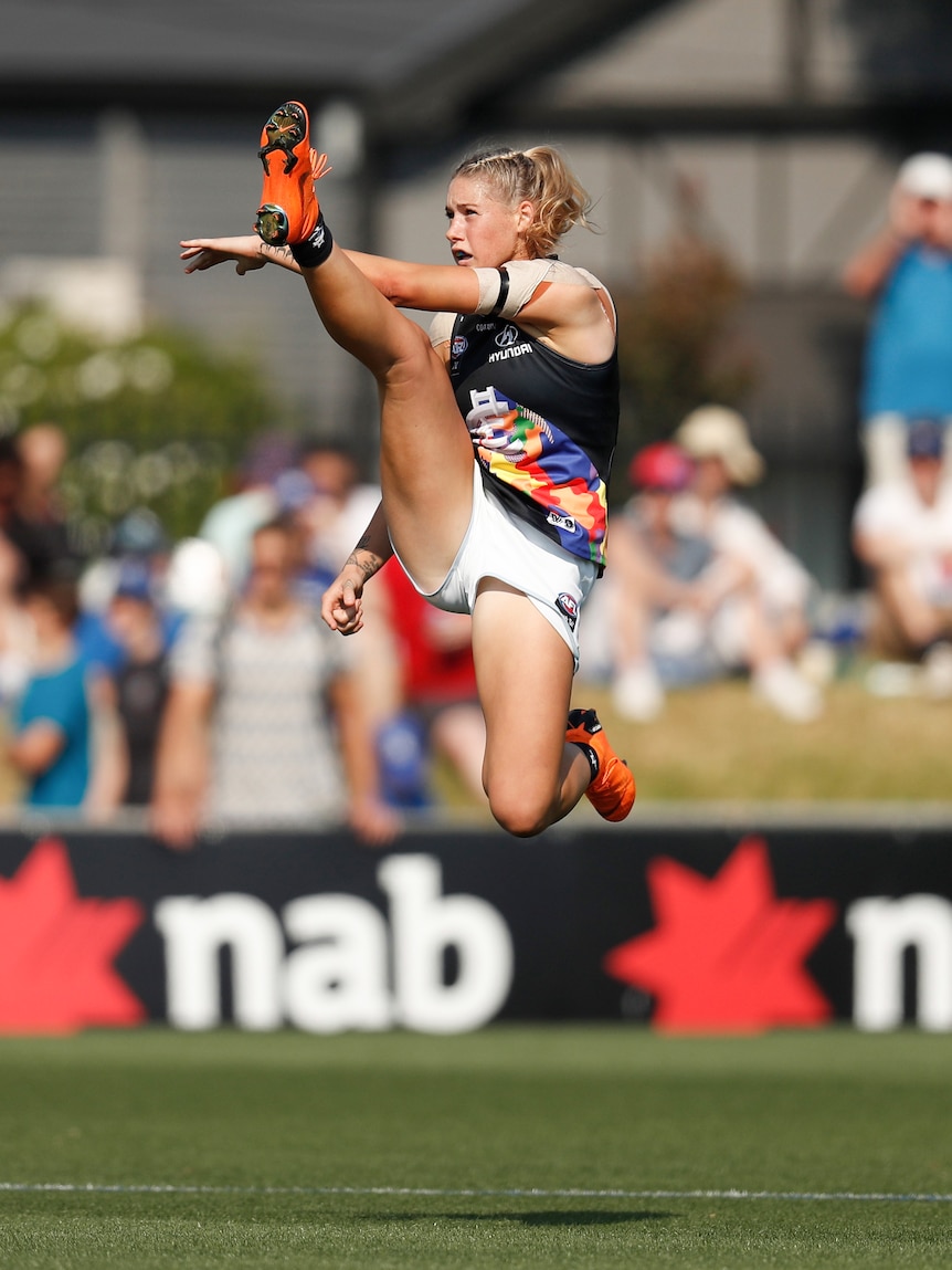 AFLw player makes a spectacular kick mid-air.