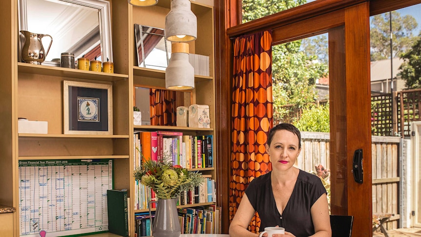 Christy Newman sits at her dining room table with a cup of tea.