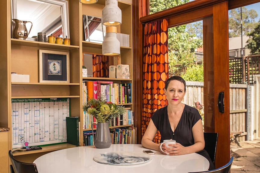 Christy Newman sits at her dining room table with a cup of tea.