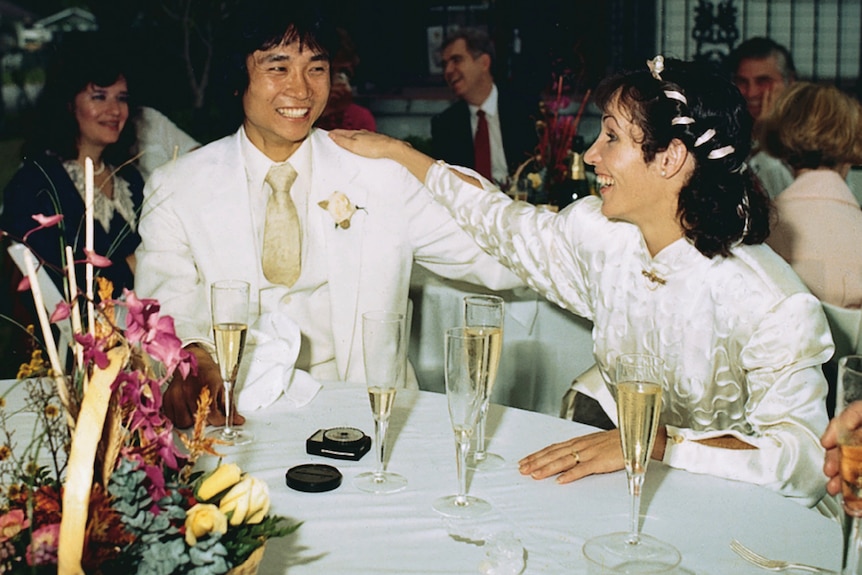 A photo from 1987 of a man and a woman seated on their wedding day, smiling