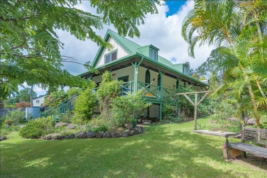 A large home with a green roof and tropical garden.