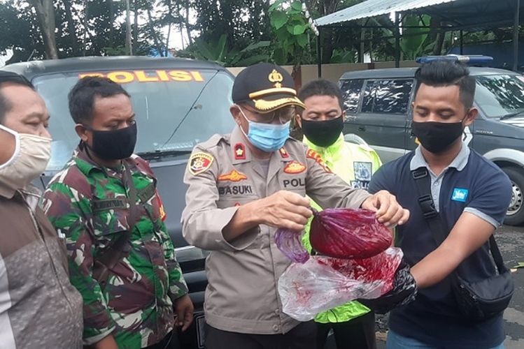A police officer in Pekalongan holds up a bag of red dye