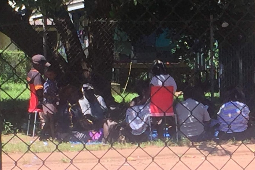 Community members photographed from behind a fence playing cards