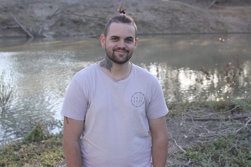 A young man stands in front of a creek