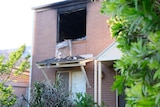 A burnt window on the upper level of a block of units.