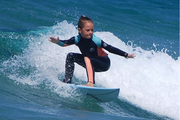 young girl surfing a wave, looking confident and focussed