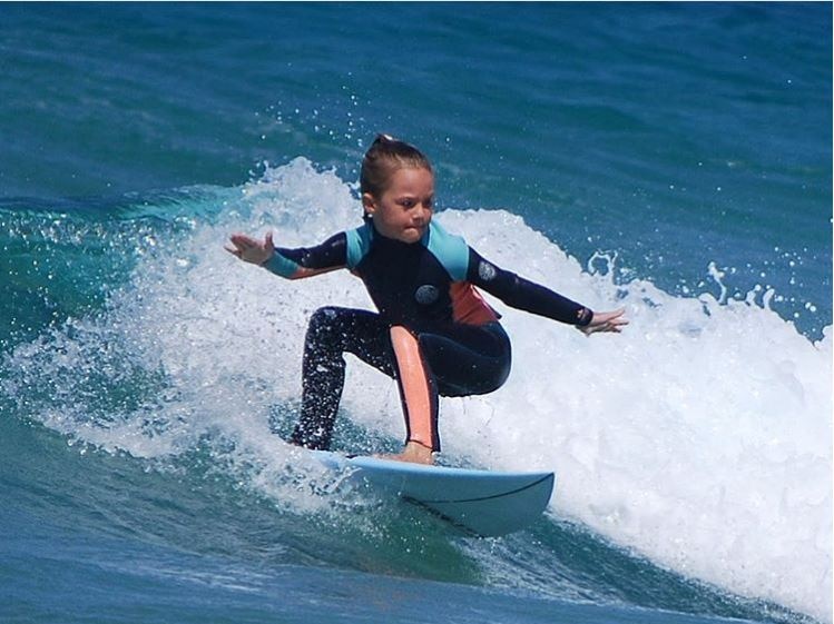 young girl surfing a wave, looking confident and focussed