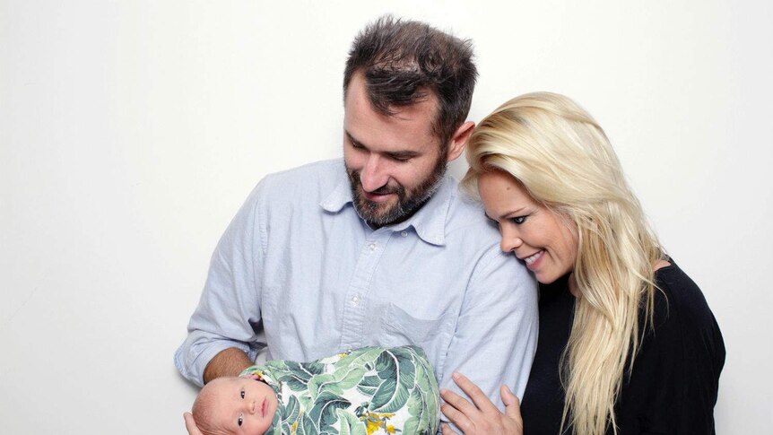 Ben and Brittan holding their daughter.