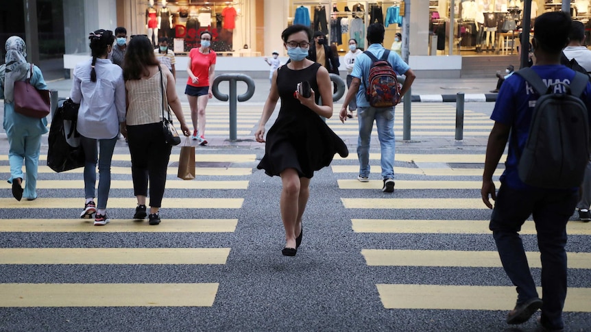 People wearing protective masks cross a street in Kuala Lumpur