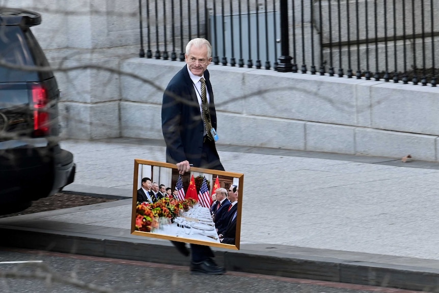 White House advisor Peter Navarro leaves the West Wing of the White House with a photograph.