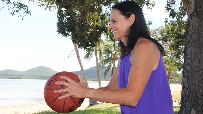 A woman throws a basketball at the beach