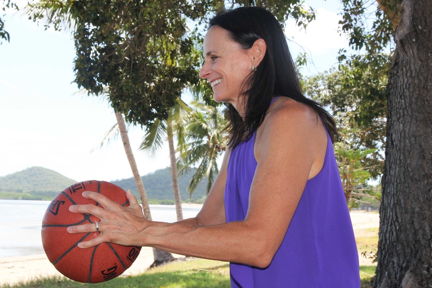 A woman throws a basketball at the beach