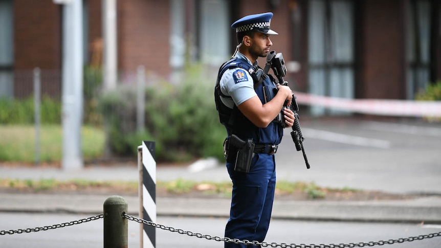 A lone police officer stands guard on Deans Avenue in Christchurch, the scene of one of the mosque shootings.