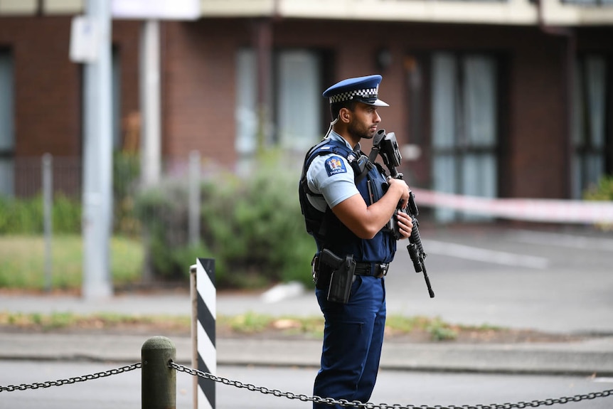 A lone police officer stands guard on Deans Avenue in Christchurch, the scene of one of the mosque shootings.