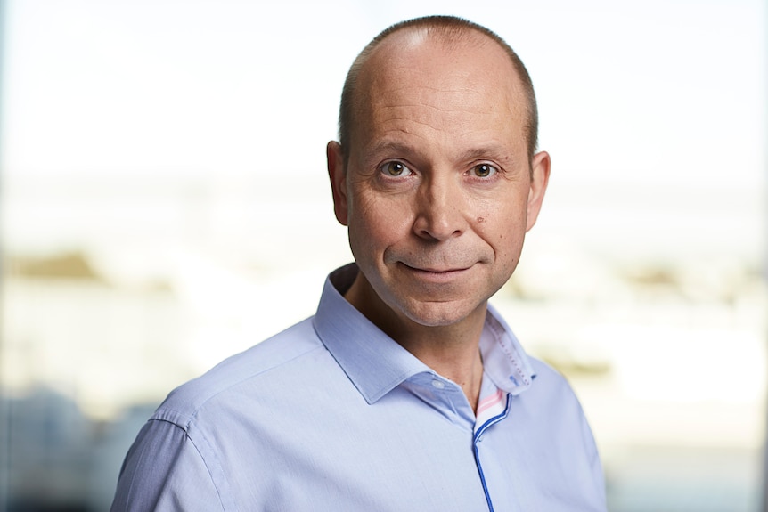 A blad man wearing a collared shirt is staring at the camera