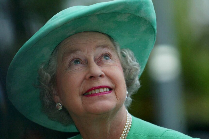 Queen Elizabeth II smiles as she glances up towards the sky.