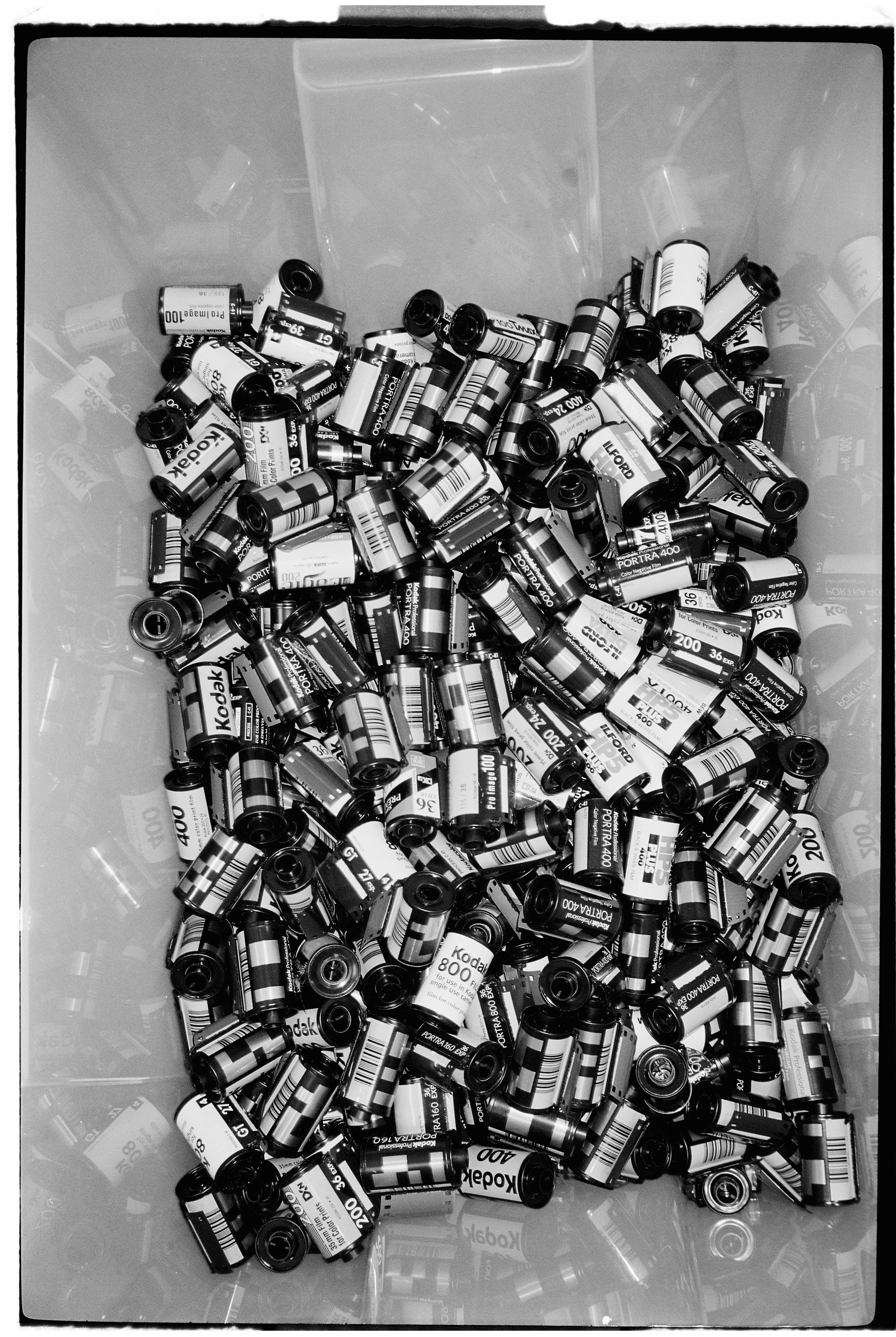 A black and white film photo of a bucket full of rolls of film