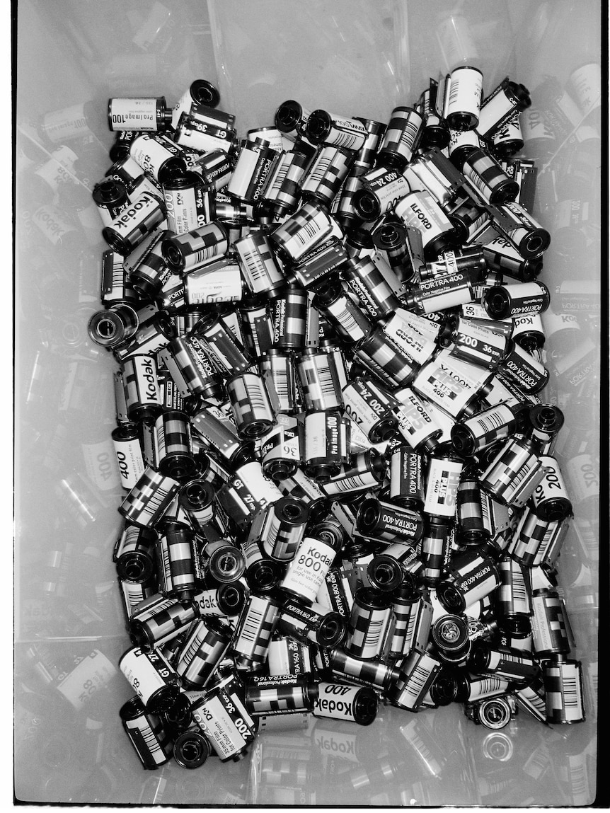 A black and white film photo of a bucket full of rolls of film