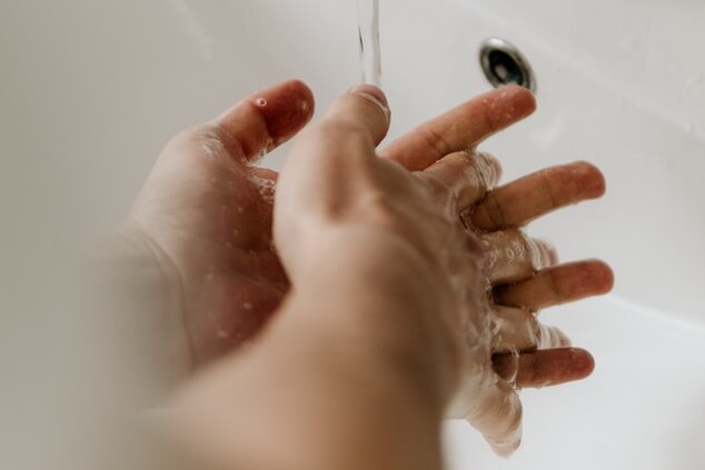 Hands being washed under tap at bathroom sink