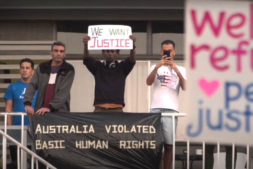 Detainees in Melbourne's detention centre protest, holding signs.