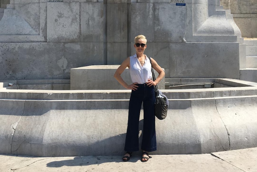 A woman with hands on her hips poses in front of a monument on a holiday. 