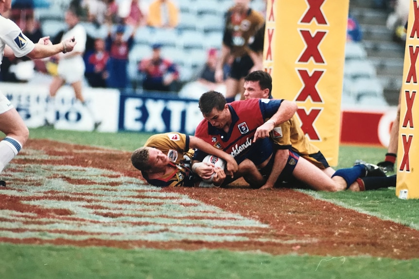 A player tries to stop an opponent from scoring a try in a rugby league match