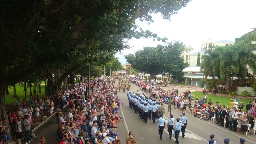 Crowds line a Townsville street cheering on the city's Anzac Day parade.