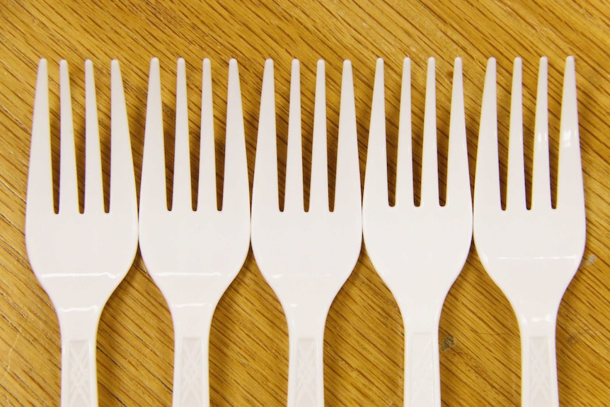 Five plastic forks in a row.
