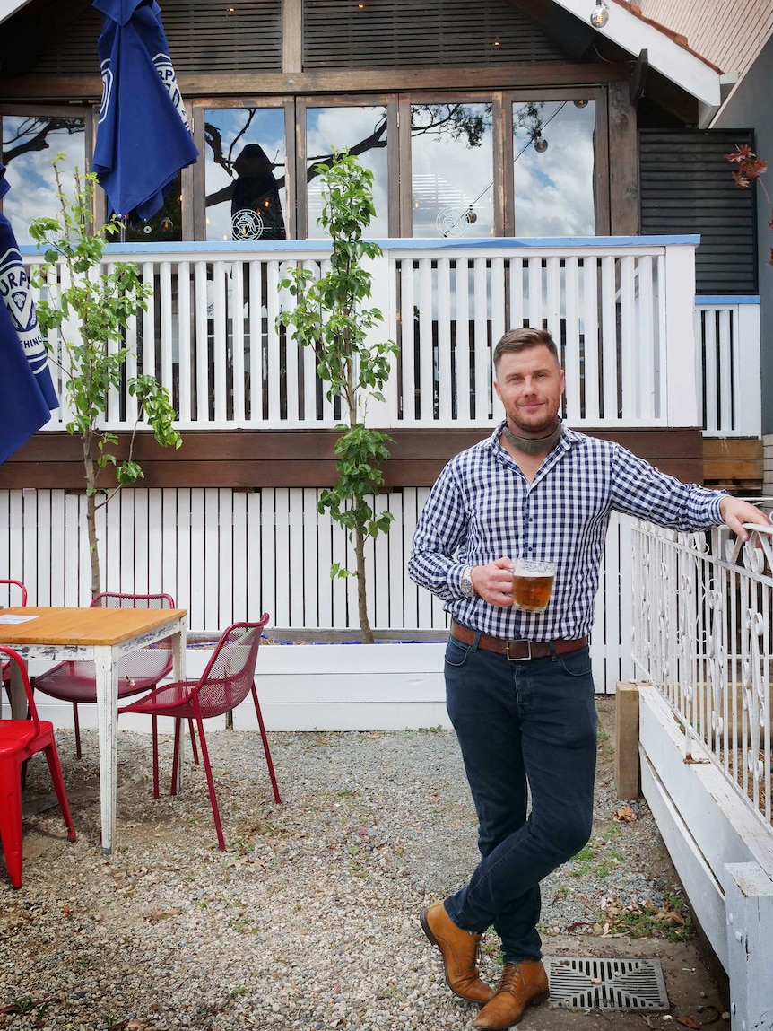 Nick Allardice holds a drink in the beer garden of his pub