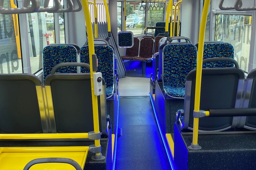 Inside the Brisbane Metro pilot bus with blue seats and yellow handrails and storage areas