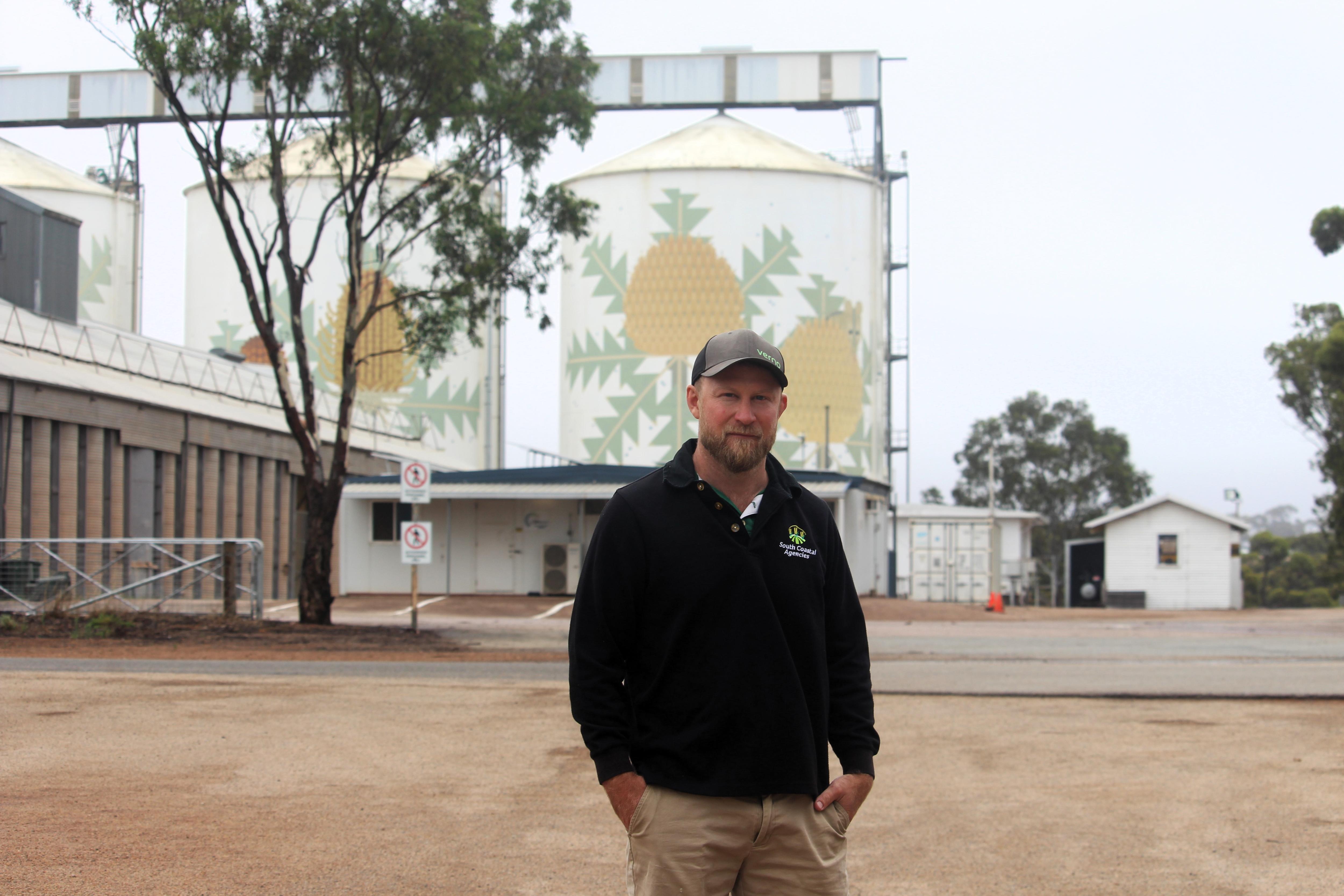 He stands in front of a grain silo