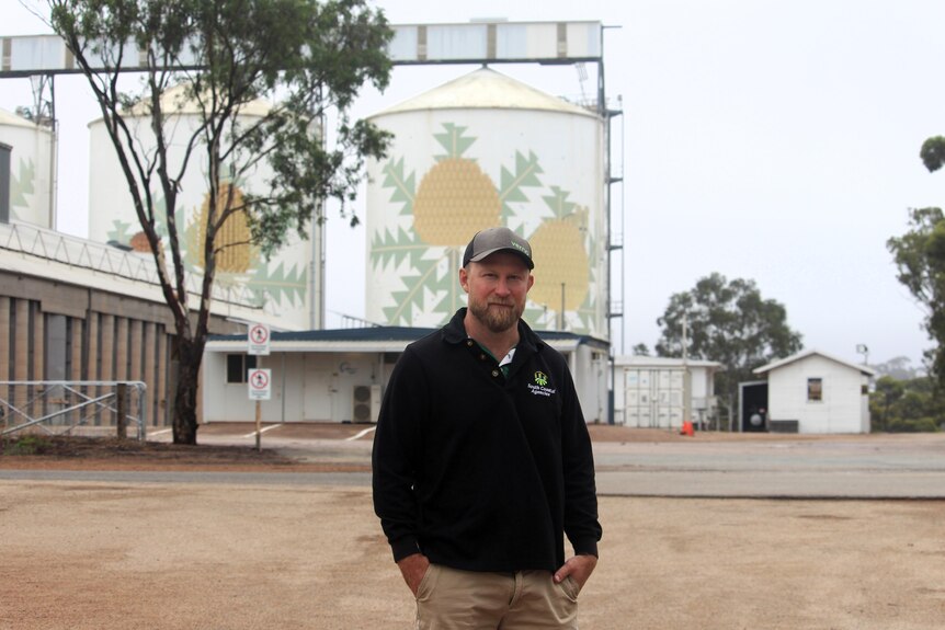 A man stands in front of a grain silo
