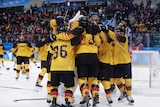 The german team shares a large group hug on the ice, celebrating their win as the crowd looks on